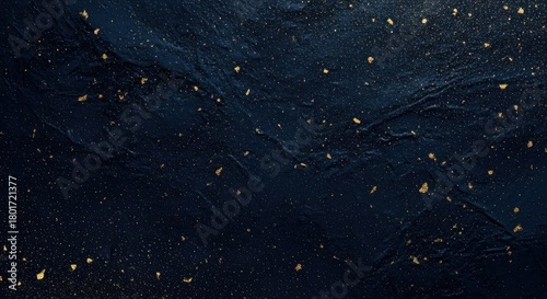 Dark textured surface with scattered gold flakes creating a striking visual effect in artistic design