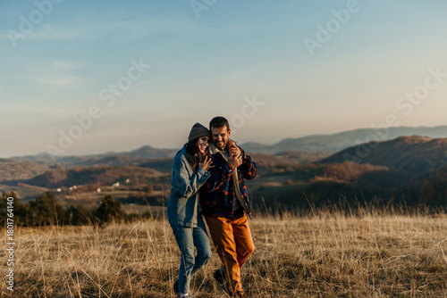 Happy couple embracing in fields enjoying nature landscape