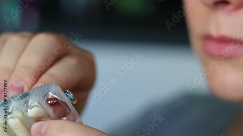 Close up of a woman taking a vitamin capsule pill out of package, filled with granules soluble