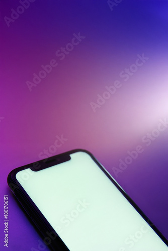 Vertical banner, smartphone with blank white screen lies on bright colorful gradient surface. Phone mock up for application interface presentation and advertising. Copy space