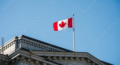 Canadian flag waving proudly on a flagpole in front of a building under a clear blue sky, symbolizing national pride and patriotism