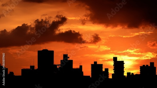 Sunset urban silhouette city skyline with orange sky and glowing sun creating dramatic dusk scenery, showing buildings, horizon, warm light, shadows and vibrant atmosphere over the modern landscape