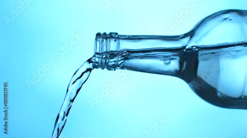 Water Flowing in a Clear Bottle on Blue Background - Liquid Motion and Purity Captured