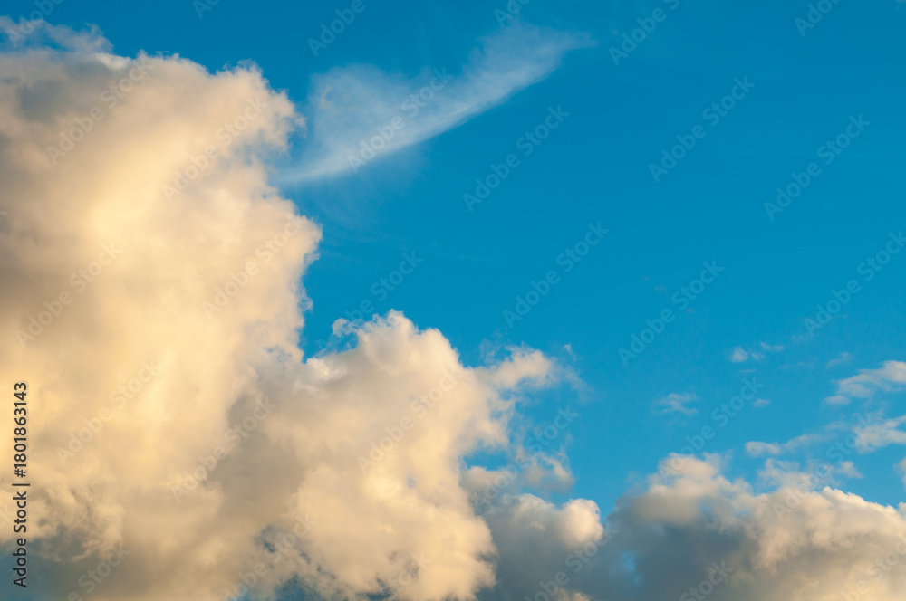 Obraz premium Sunset sky landscape with golden fluffy clouds in the blue sky, evening sky view