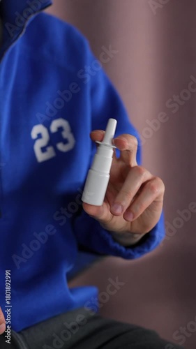 A man in a blue sweater uses a nasal spray.
Runny nose and difficulty breathing.
Nasal drops in a plastic bottle.