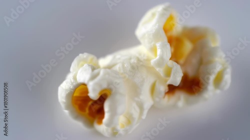 Close up macro shot of a single piece of popcorn on a plain background.