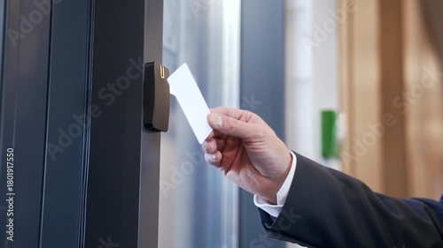 Close up of male hand using key card to open door of office with electronic smart lock. Businessman using identity keycard at sensor control security system. Smart card unlocks modern entry secure