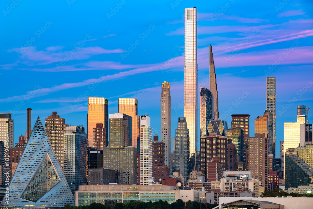 Obraz premium A twilight panorama of the magnificent Midtown Manhattan skyline, seen from across the Hudson River, prominently featuring the colossal towers of Billionaires' Row.