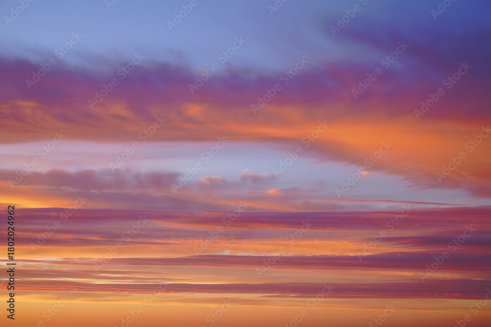 Naklejka premium Vibrant sunset sky with streaks of orange pink and purple clouds painting the horizon in a breathtaking display