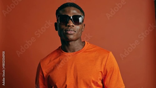 Vibrant Orange Themed Portrait of Stylish Young African American Man Wearing Sunglasses and Striking a Pose