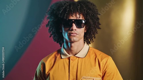 Fashion Portrait of Curly Haired African American Man in Orange Shirt and Shades Against Colorful Backdrop