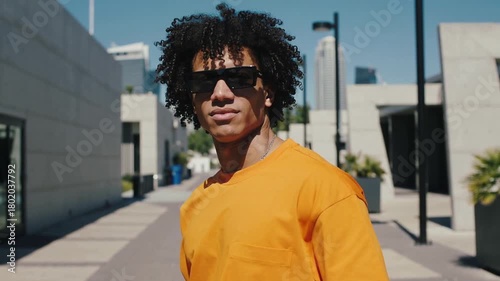 Modern and Energetic Shot of Curly Haired African American Man Wearing Orange Clothing and Sunglasses