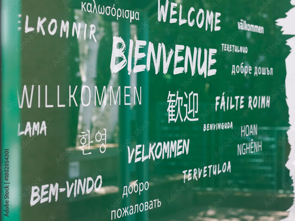 Naklejka premium welcome text in multiple languages of various country in a wall green