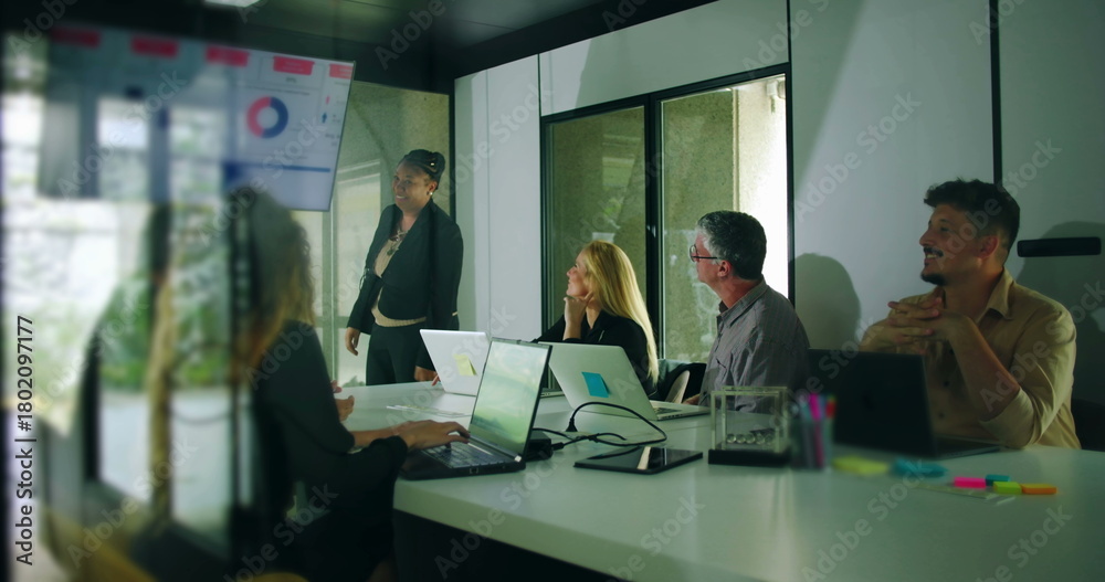 Fototapeta premium African American presenter smiling after delivering business presentation while colleagues respond positively in team meeting environment