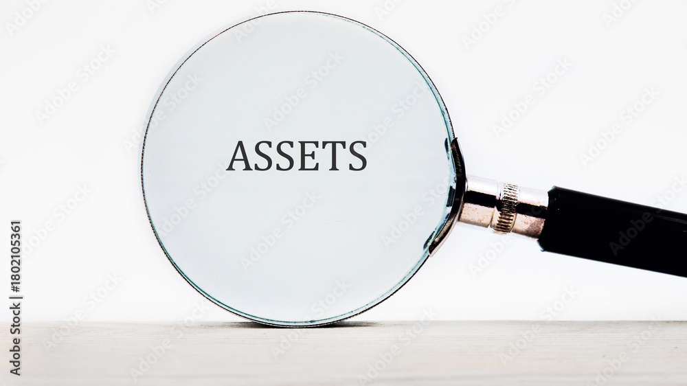Fototapeta premium A magnifying glass focuses on the word ASSETS, symbolizing the quest for clarity and understanding in financial matters and wealth management during a detailed investigation