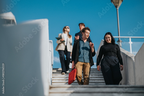 Slika na platnu A group of young professionals walks down white stairs outdoors on a sunny day