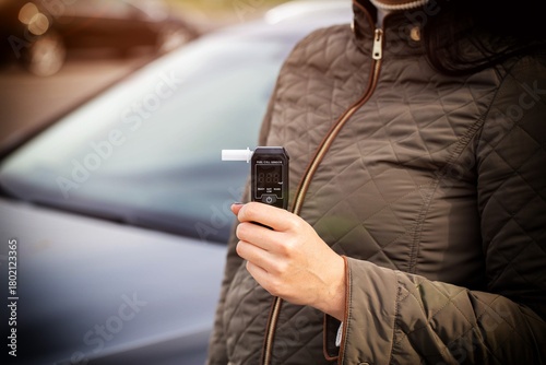 Woman Holding Digital Breathalyzer Before Driving. Responsible Driver Checks Alcohol Level. Copy space for text. Driving license revocation for alcohol