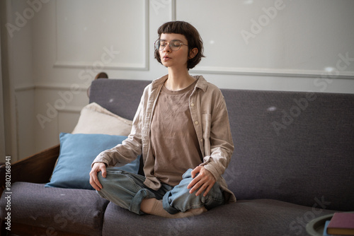 Quadro su tela Absorbed woman in cross legged pose on couch inhale and exhale slowly