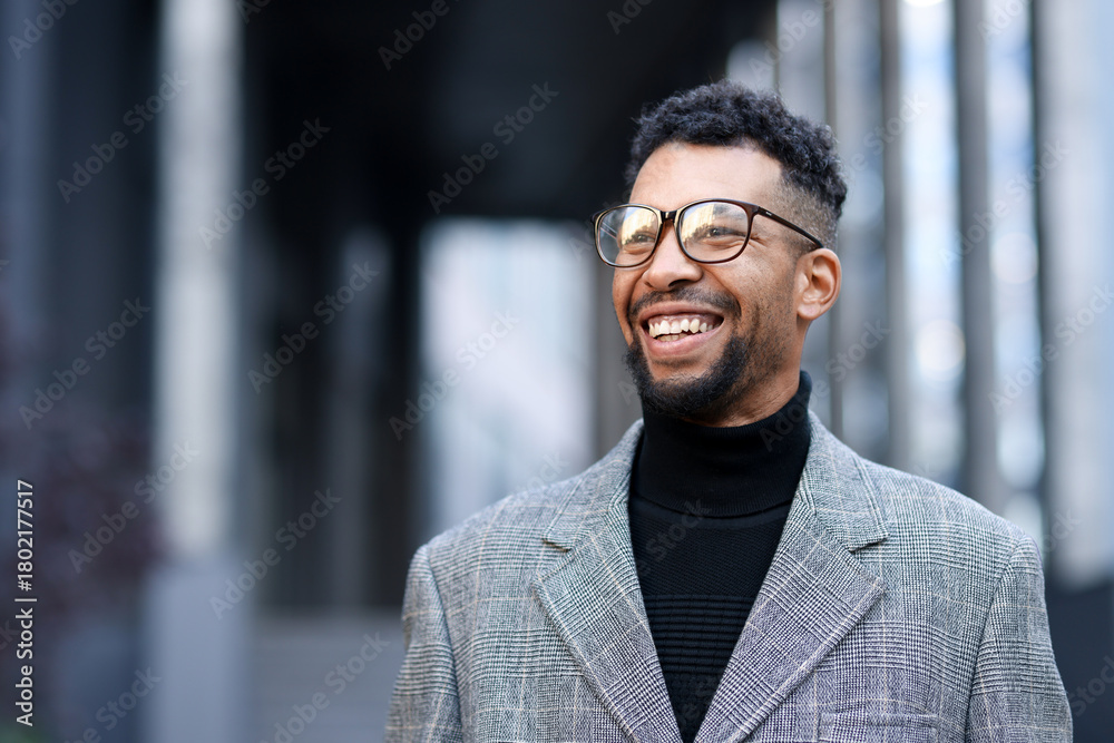 Fototapeta premium Smiling man in glasses and suit on city street. Space for text