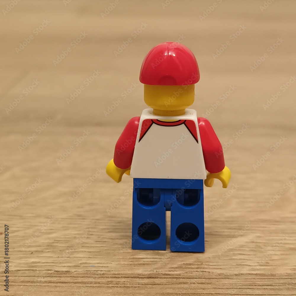 Fototapeta premium Rear view of a Lego figure wearing a red cap and white shirt, representing childhood memories and play