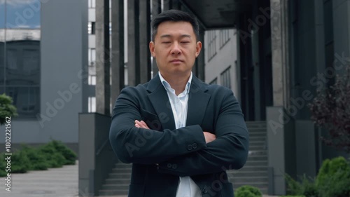 Motivated serious 40s Chinese ethnic business man crossing hands looking at camera Japanese middle-aged businessman adult Asian Korean male entrepreneur formal manager crossed arms power pose in city
