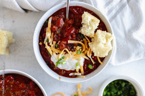 Fotografia Overhead view of a hearty bowl of chili topped with shredded cheese, sour cream, and sliced green onions