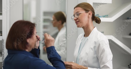 Wallpaper Mural Young female optician assisting senior woman in eyewear store Torontodigital.ca