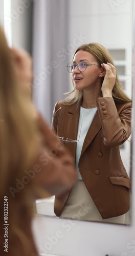 Woman trying new eyeglasses in front of mirror