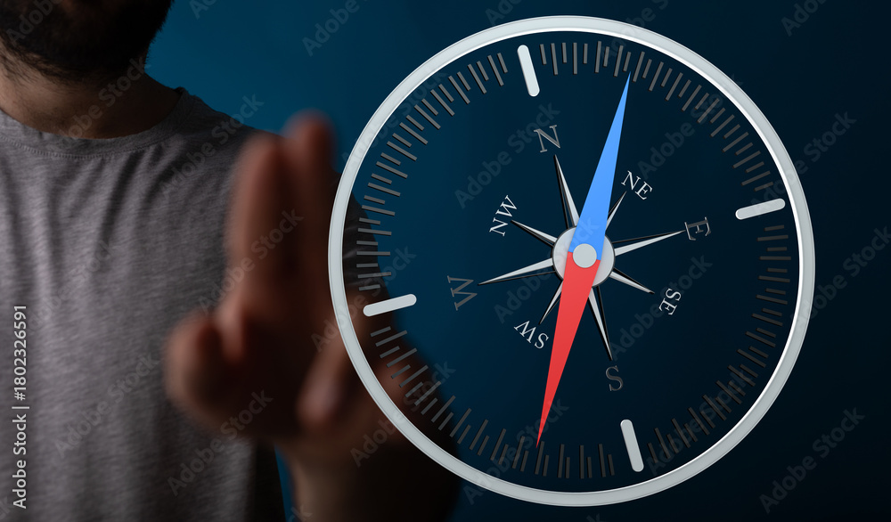 Fototapeta premium A person's finger pointing towards a compass, symbolizing navigation, direction, and guidance. Concept of finding your way, achieving goals and