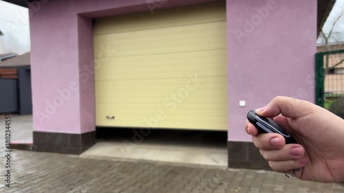 Person is operating a remote control opening a garage door or gate for a car