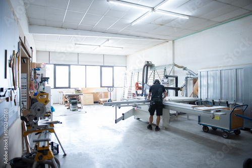 Moderne Werkstatt mit Holzbearbeitungsmaschinen und Handwerker bei der Arbeit