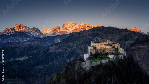 view of Hohenwerfen Castle at sunrise and the illuminated mountains