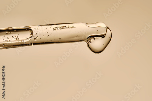 The texture of the serum flowing out of the pipette on a beige background.