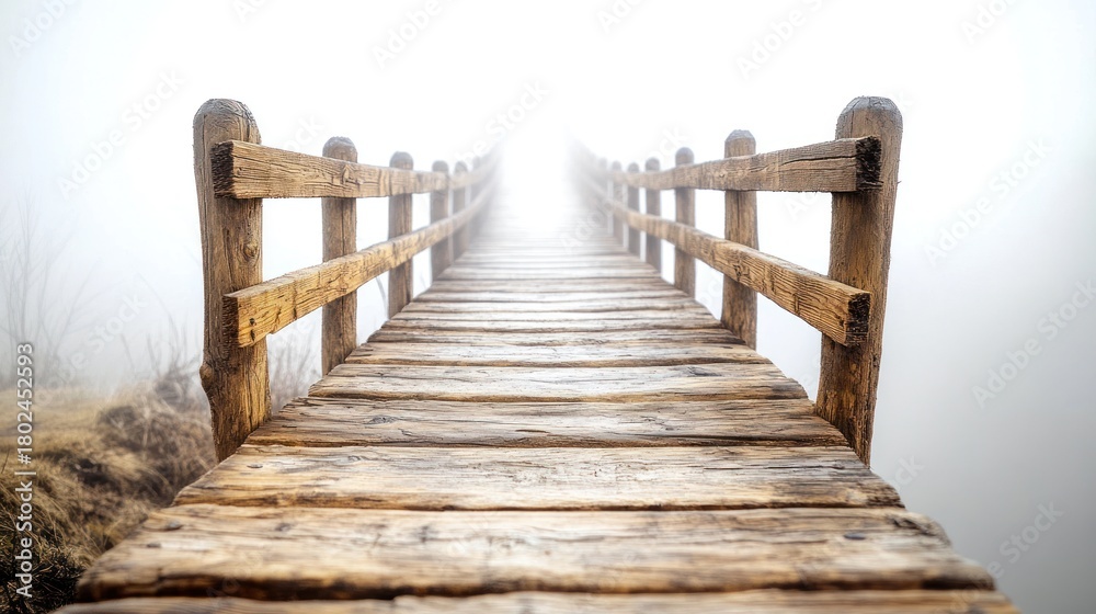 Obraz premium A rustic wooden bridge stretches ahead through dense fog, creating a tranquil atmosphere