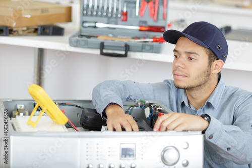 happy young male electrician fixing a washer