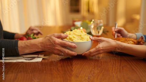 Hands passing bowl of mashed potatoes at dinner table