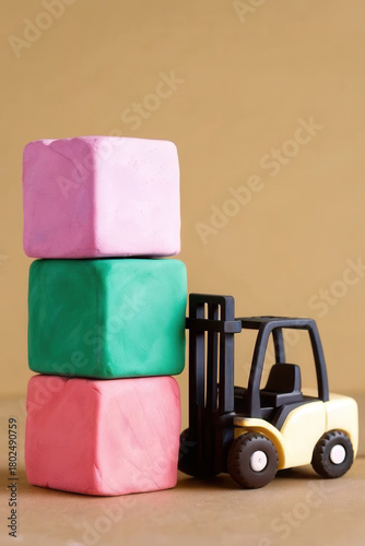 Tiny clay forklift placed beside tall colorful clay cubes, creating playful and creative scene with soft pastel tones