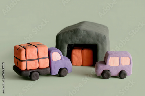Simple clay logistics scene with purple truck carrying orange boxes near warehouse and small car on neutral background
