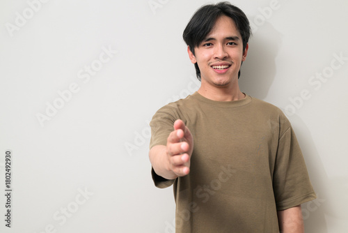 Portrait of handsome Young Asian Thai man offering handshake against white background
