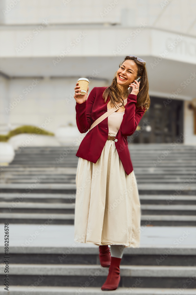 Fototapeta premium Business woman talking on the phone outdoors. Young woman talking on mobile phone walking in the street.