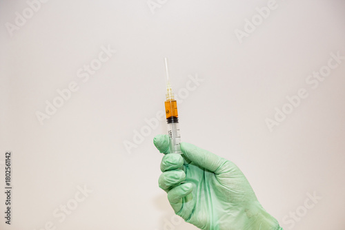 A cosmetologist in a white coat and gloves checks and demonstrates a blood collection tube with centrifuged blood - separated rich in platelets and plasma