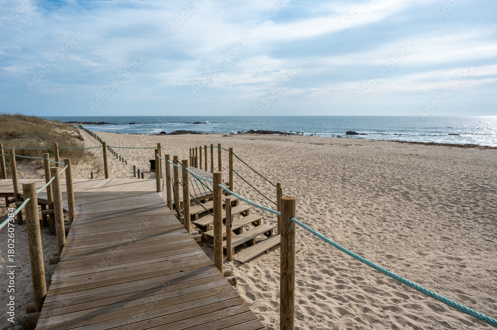Obraz premium Boardwalk over dunes of Canide Beach on northern coast of Portugal in Vila Nova de Gaia under dramatic autumn cloudscape.