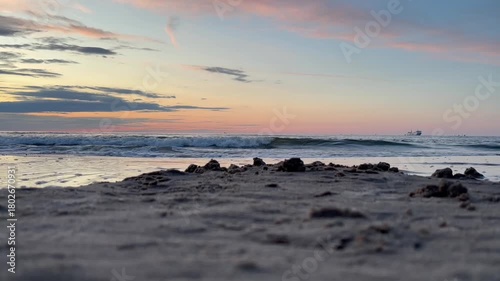Peaceful golden-hour waves gently rolling onto the sandy shore under a dramatic, colorful sunset sky. Perfect for relaxation, travel, and nature-themed projects.