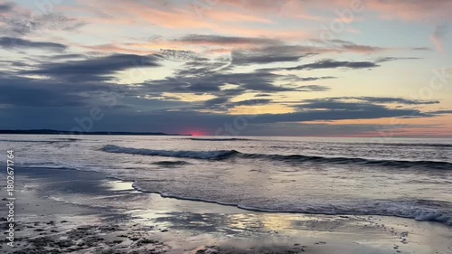 Stunning sunset illuminating the calm ocean with soft pink and orange hues. Gentle waves create a soothing, cinematic coastal atmosphere. High quality FullHD footage