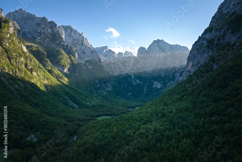 Prokletije (Accursed Mountains) aerial panorama at sunrise — dramatic karst peaks over a deep green valley, Montenegro