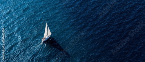 Sailboat Gliding Across a Deep Dark Blue Ocean from an Aerial View