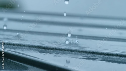 Close up of raindrops splashing on a grooved surface creating a beautiful water droplet display