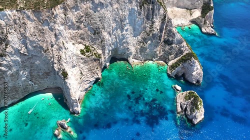 Aerial drone cinematic video of tropical exotic island bay with steep white cliffs and sea caves creating a blue lagoon visited by small tourist boats