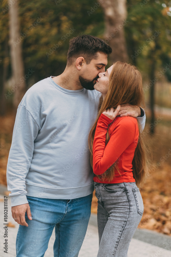 Fototapeta premium youthful pair with bright autumn backdrop, smiling duo dressed in colorful attire amidst fall scenery