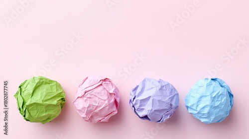 Colorful Crumpled Paper Balls on a Soft Pink Background Showcasing Creativity and Playfulness in a Minimalist Design